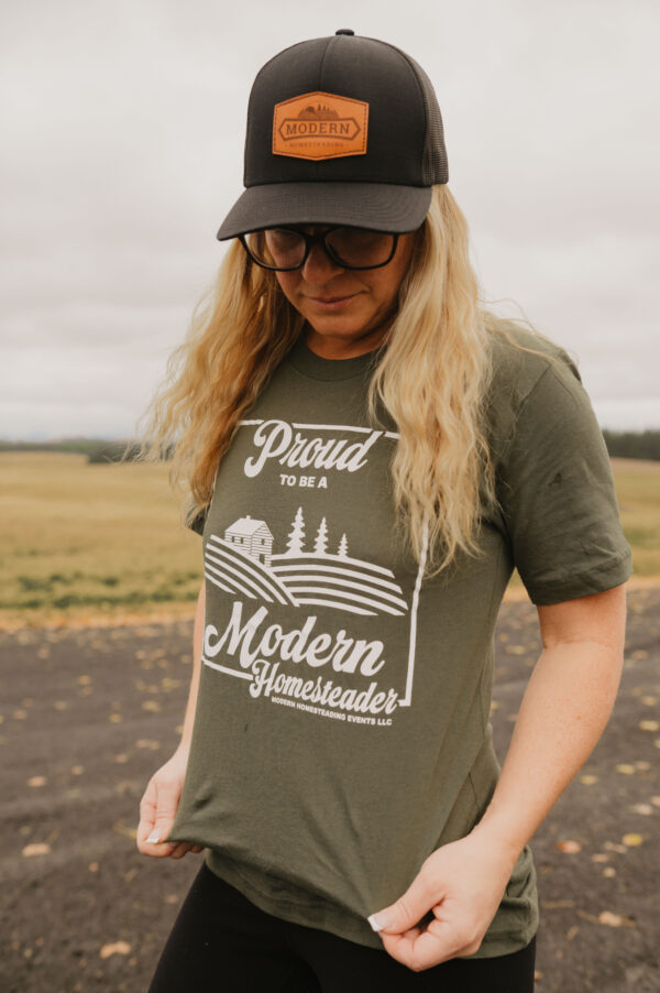 Woman in olive green proud to be a Modern Homesteader t-shirt in a field